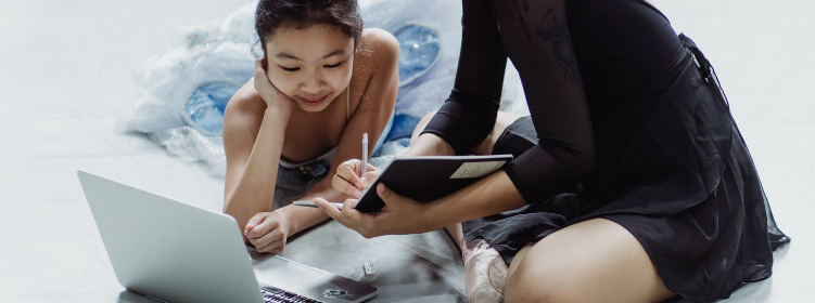 A cheerful mother and her daughter are using an educational website for kids on their laptop and taking notes